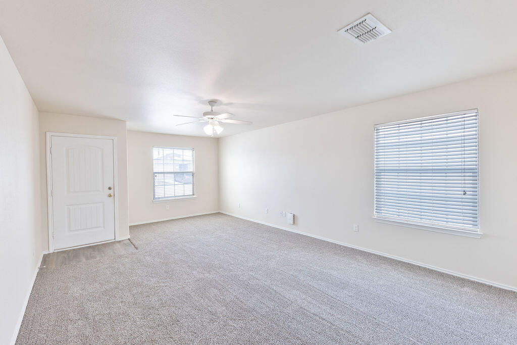 8907 Terrell Avenue Lubbock, TX 79423 - Photo 2 of 8 an empty room with windows and chandelier fan