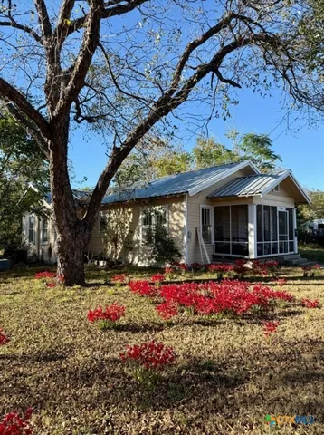 a front view of a house with a yard and a large tree
