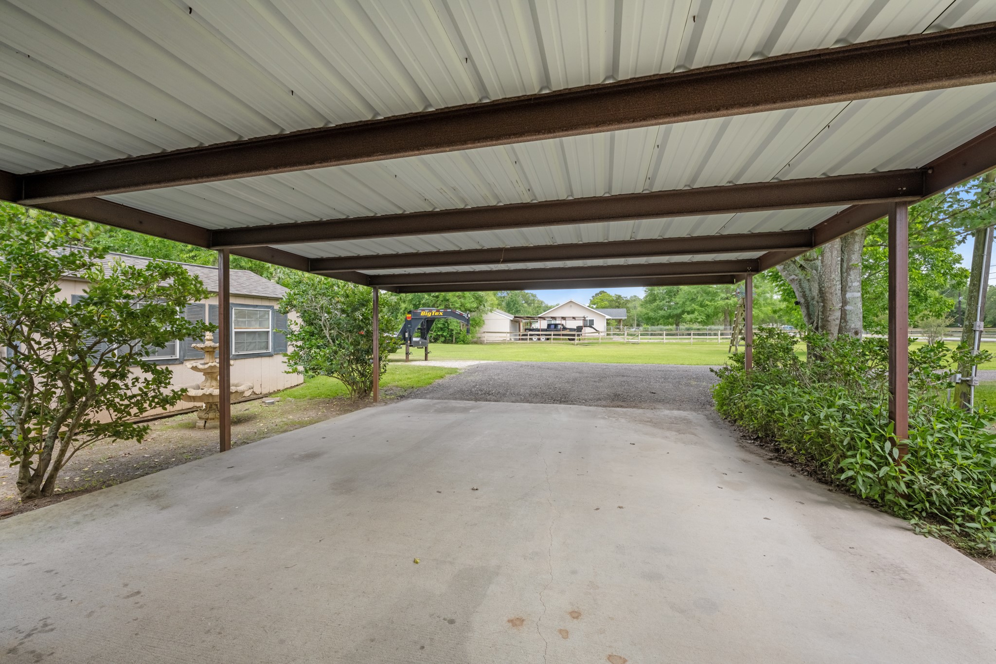 15602 Fir Road Santa Fe, TX 77517 - Photo 26 of 42 Covered parking area with ample space for two vehicles, trailers, or recreational equipment. The surrounding open yard and mature landscaping add to the property’s versatility and country-style appeal.
