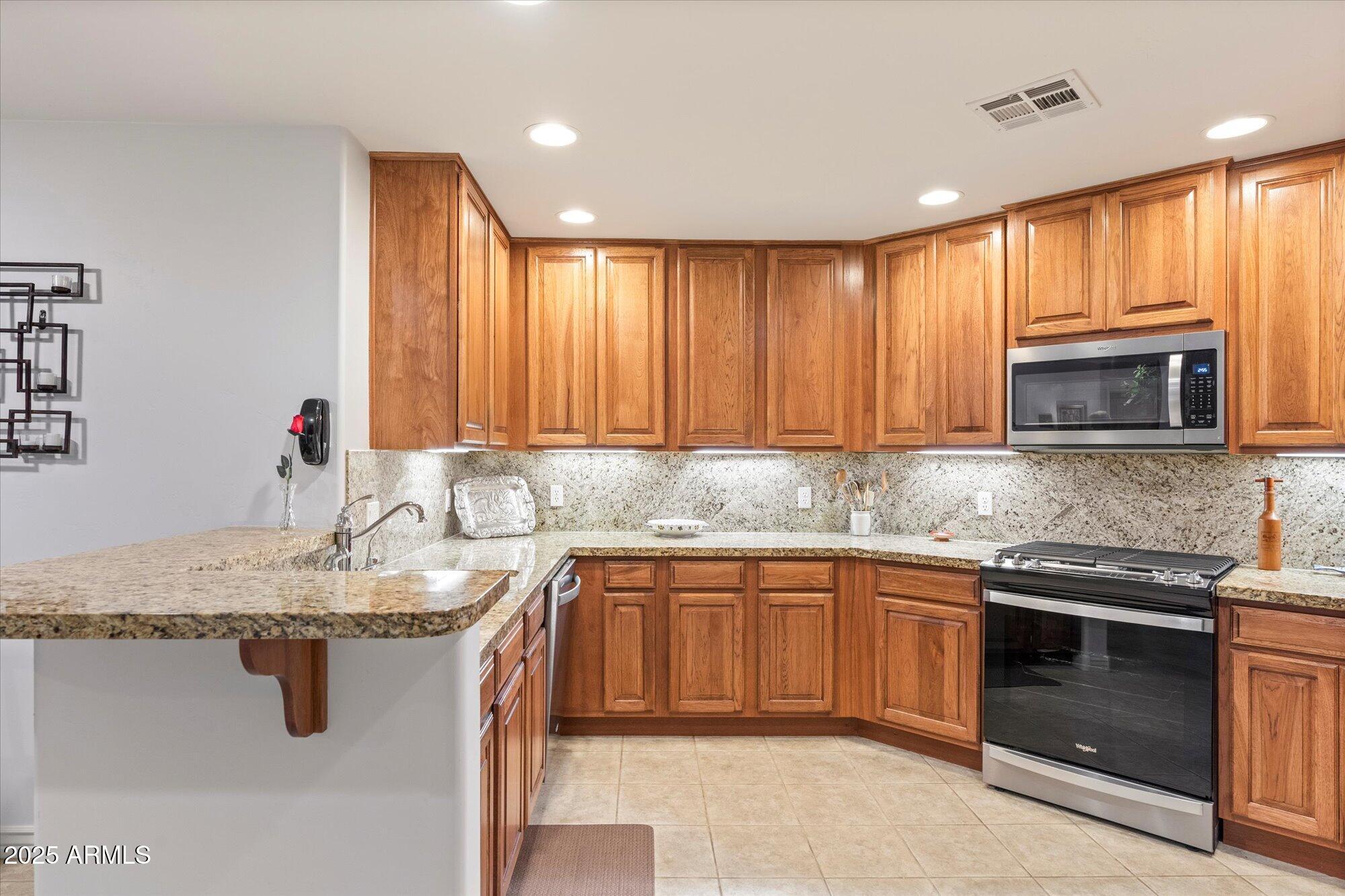 5350 East Deer Valley Drive, Unit 1238 Phoenix, AZ 85054 - Photo 2 of 29 a kitchen with stainless steel appliances granite countertop a sink stove and cabinets