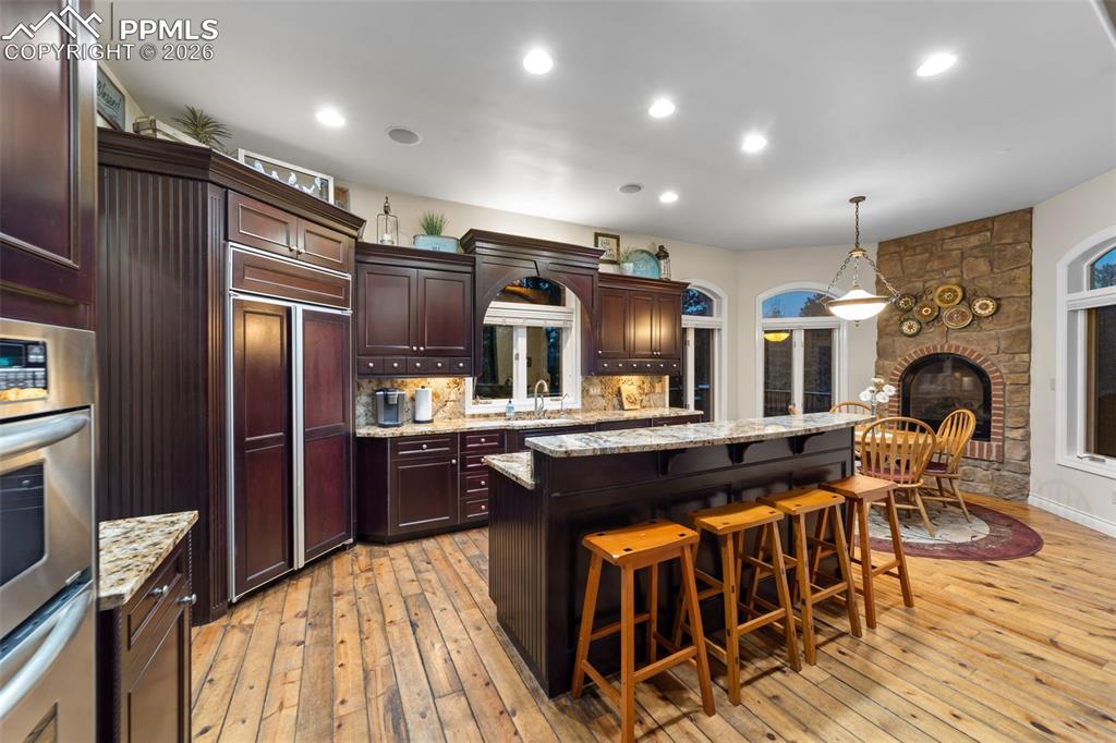4450 Abert Ridge View Colorado Springs, CO 80908 - Photo 13 of 50 a kitchen with stainless steel appliances granite countertop a refrigerator a stove top oven and a dining table with wooden floor