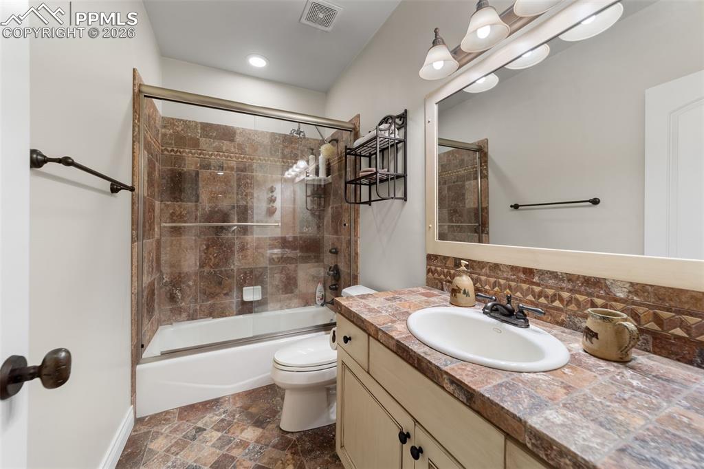 4450 Abert Ridge View Colorado Springs, CO 80908 - Photo 41 of 50 a bathroom with a granite countertop sink a toilet a mirror and shower