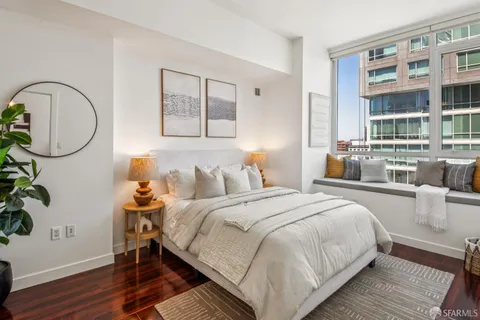 a bedroom with bed and a potted plant with wooden floor