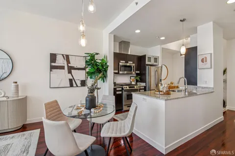 a kitchen with stainless steel appliances kitchen island granite countertop a refrigerator a stove a sink dishwasher and a dining table with wooden floor