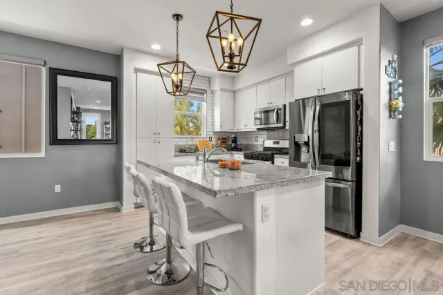 a kitchen with stainless steel appliances kitchen island granite countertop a refrigerator a stove a microwave oven a sink with island and chairs