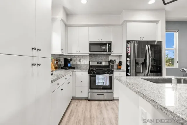 a kitchen with granite countertop a refrigerator stove and sink