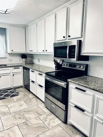 a kitchen with granite countertop white cabinets and white appliances