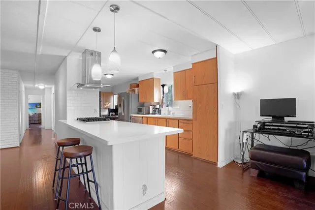 a kitchen with stainless steel appliances granite countertop a stove a refrigerator a oven a sink a dining table and chairs with wooden floor