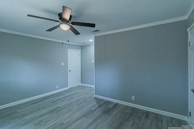 an empty room with wooden floor fan and windows