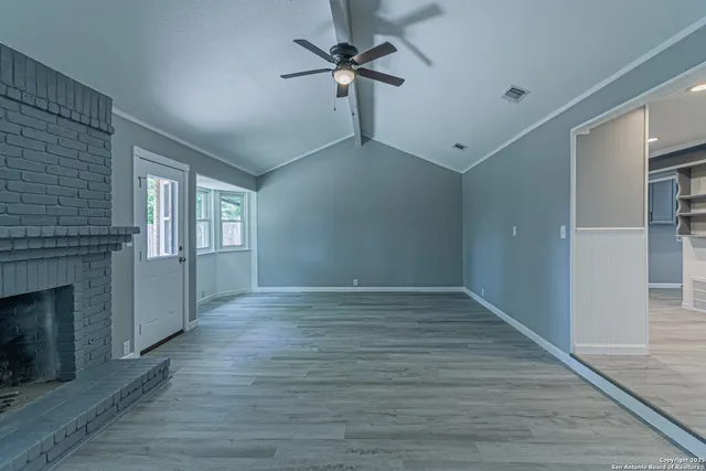 a view of an empty room with a fireplace and a window