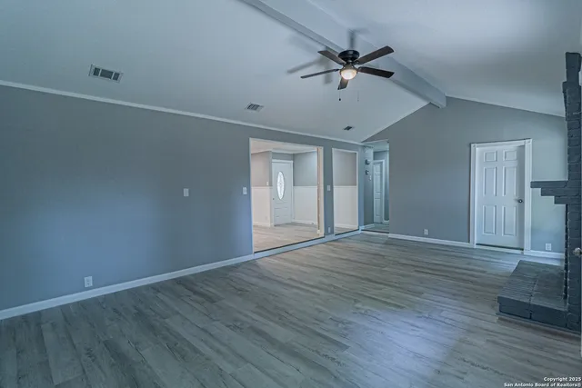 a view of an empty room with a window and wooden floor