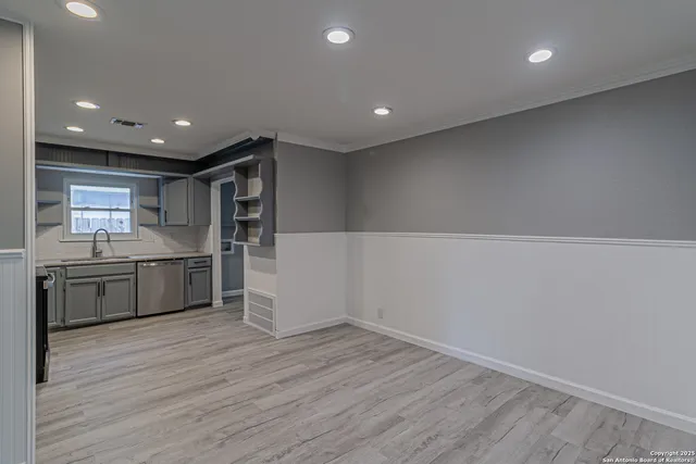 a large white kitchen with a sink and dishwasher a stove top oven with wooden floor