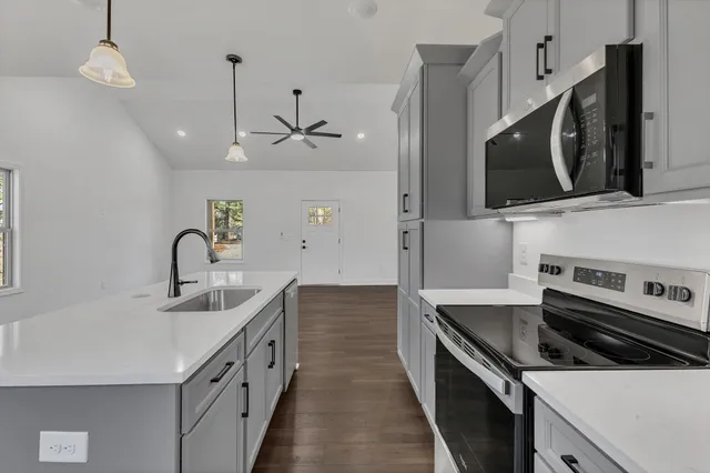 an empty room with wooden floor chandelier fan and windows