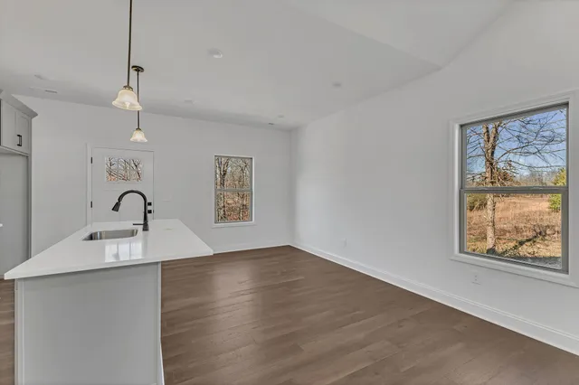 an empty room with wooden floor ceiling fan and windows