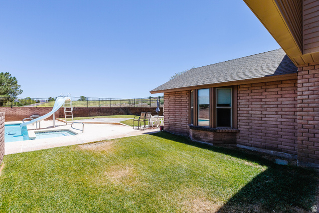 1470 Redwood Tree Street St. George, UT 84790 - Photo 48 of 53 Expansive backyard featuring a rectangular swimming pool with integrated spa and slide, concrete surround, and a manicured lawn