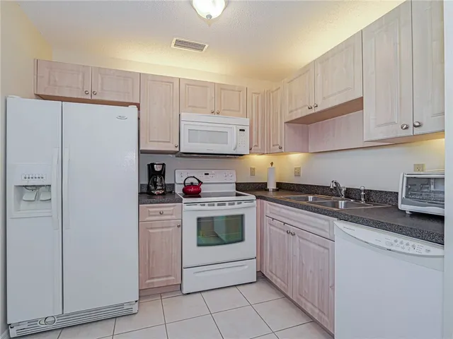 a kitchen with granite countertop white cabinets and white appliances