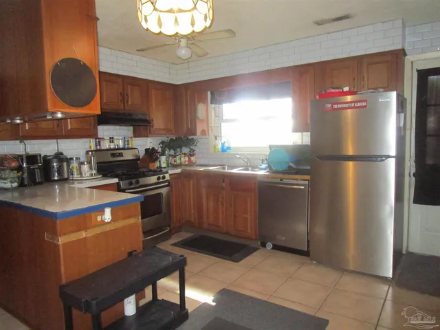 a kitchen with stainless steel appliances granite countertop a refrigerator a sink dishwasher a stove with wooden cabinets and floor