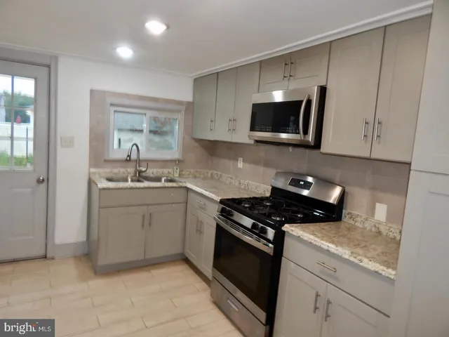 a kitchen with sink a microwave a stove and cabinets
