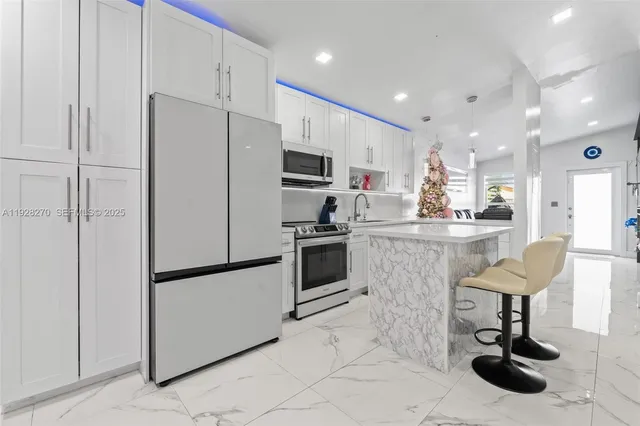a kitchen with stainless steel appliances kitchen island granite countertop a refrigerator and a stove top oven