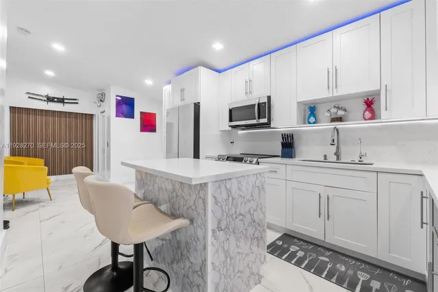 a kitchen with stainless steel appliances kitchen island granite countertop a sink and a refrigerator