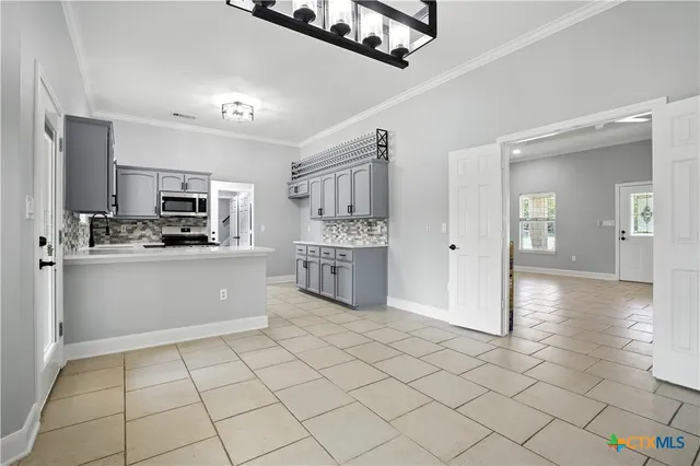 a kitchen with kitchen island granite countertop a stove top oven a sink a counter top space and cabinets