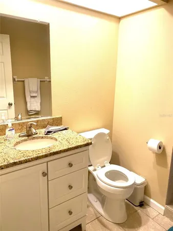 a bathroom with a granite countertop toilet sink and mirror