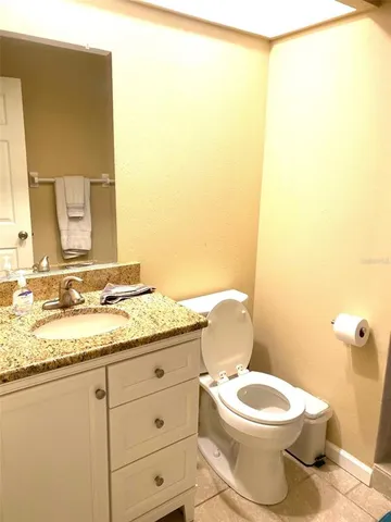 a bathroom with a granite countertop toilet sink and mirror