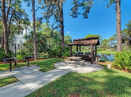 a view of a patio with table and chairs and potted plants and large trees