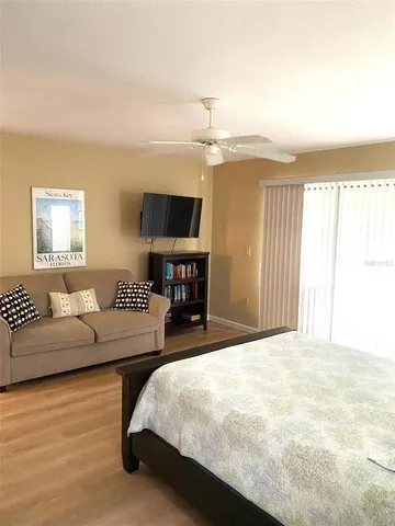 a spacious bedroom with a bed a couch and a flat tv screen on dresser