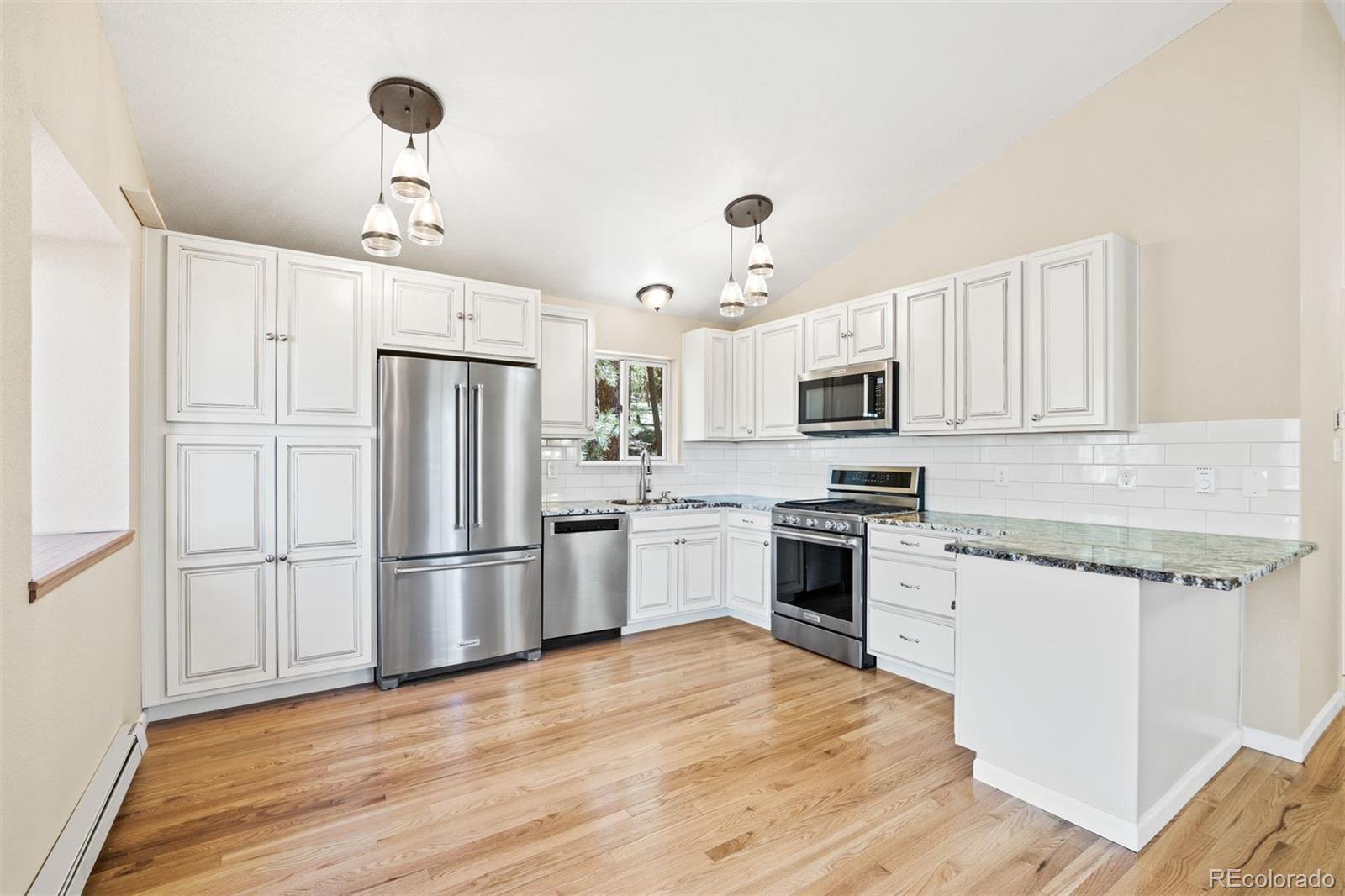122 South Random Road Bailey, CO 80421 - Photo 9 of 38 a kitchen with stainless steel appliances granite countertop a refrigerator a stove oven a sink dishwasher and white cabinets with wooden floor