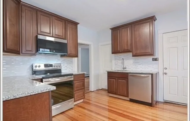 a kitchen with granite countertop wooden cabinets and a stove top oven