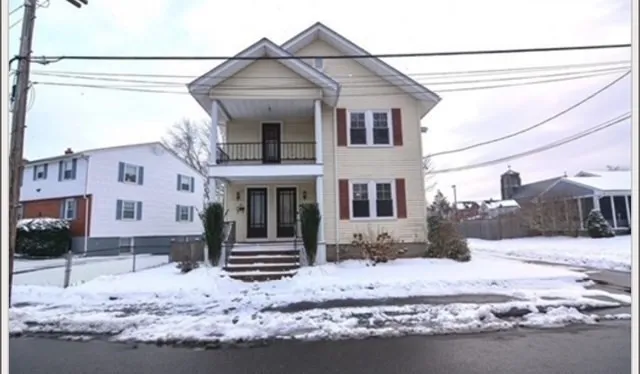 a view of a white house with snow on the road