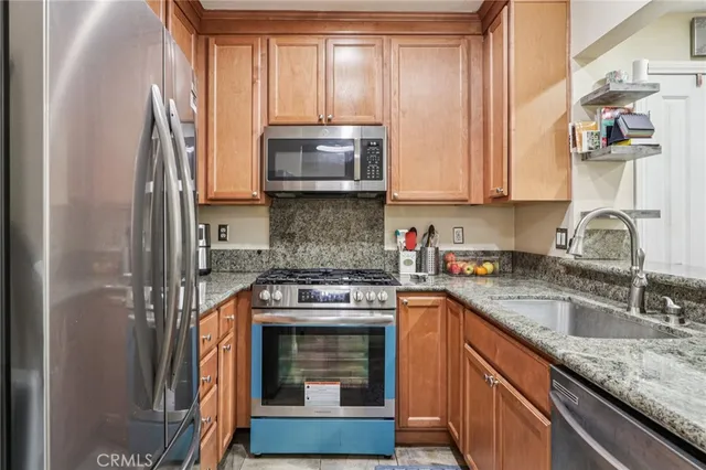 a kitchen with stainless steel appliances granite countertop a stove a sink and a microwave