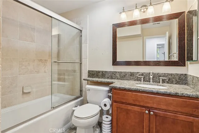 a bathroom with a granite countertop sink toilet and shower