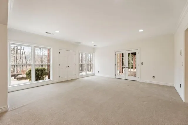 an empty room with chandelier fan and windows