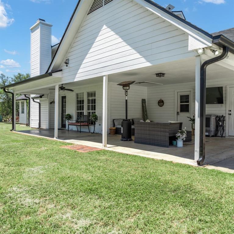 Expansive covered patio featuring a concrete surface, white support columns, and two ceiling fans