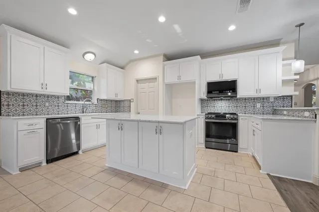 a kitchen with kitchen island granite countertop a stove sink and cabinets