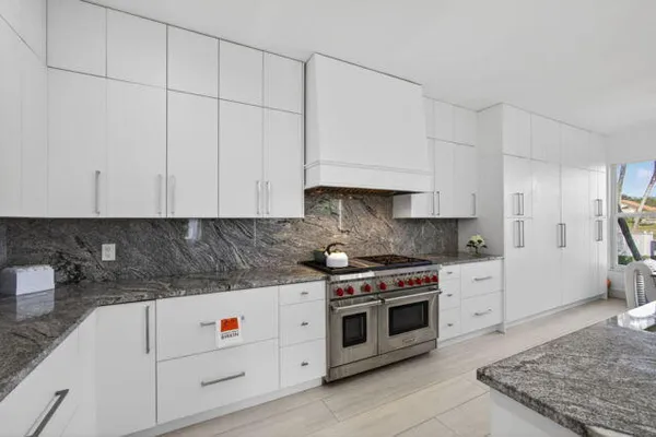 a kitchen with stainless steel appliances granite countertop a stove a sink and a white cabinets