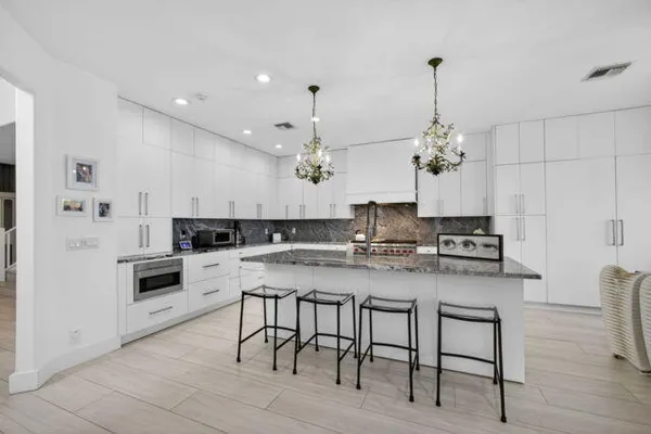 a kitchen with kitchen island granite countertop a sink cabinets and wooden floor