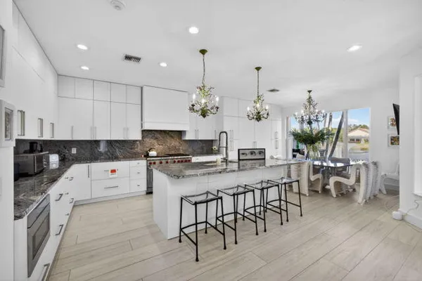 a kitchen with stainless steel appliances a dining table chairs stove and cabinets