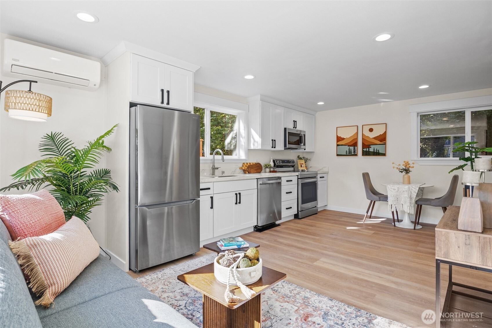 9545 Wallingford Avenue North Seattle, WA 98103 - Photo 6 of 22 a kitchen with stainless steel appliances a refrigerator a stove a sink dishwasher a dining table and chairs with wooden floor