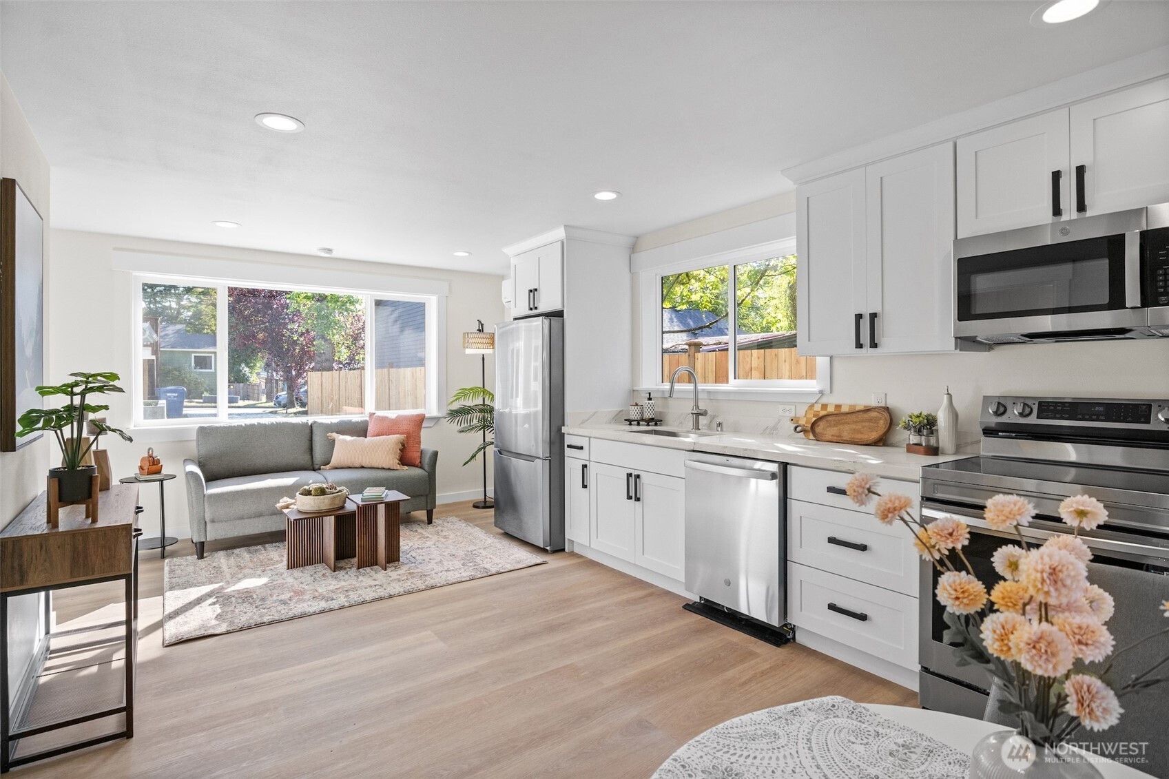 9545 Wallingford Avenue North Seattle, WA 98103 - Photo 8 of 22 a open kitchen with stainless steel appliances granite countertop a stove top oven a sink dishwasher a dining table and chairs with wooden floor