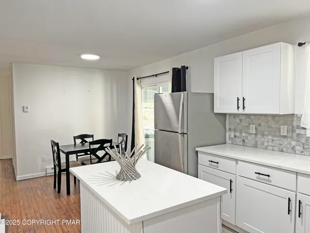 a kitchen with a refrigerator a stove a dining table and chairs