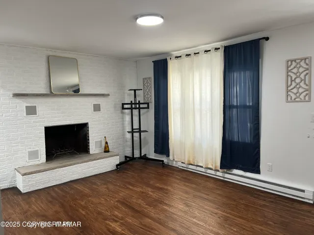 an empty room with wooden floor fireplace and windows
