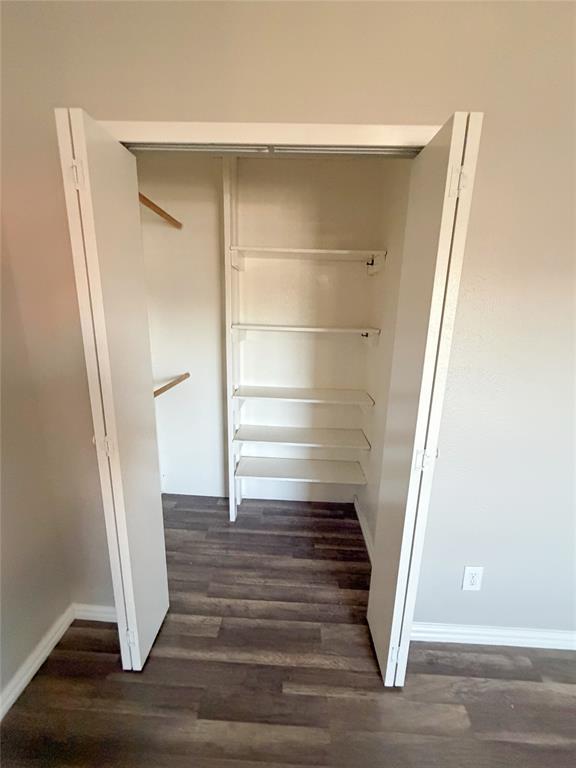 8601 Woodside Road Rowlett, TX 75088 - Photo 18 of 22 White bi-fold closet doors with interior shelving and clothing rods, set against wood-finish flooring