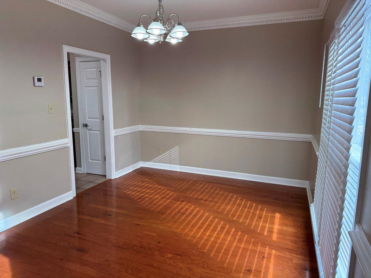 8810 Raspberry Lane Memphis, TN 38016 - Photo 14 of 28 Unfurnished room featuring baseboards, a notable chandelier, crown molding, and wood finished floors