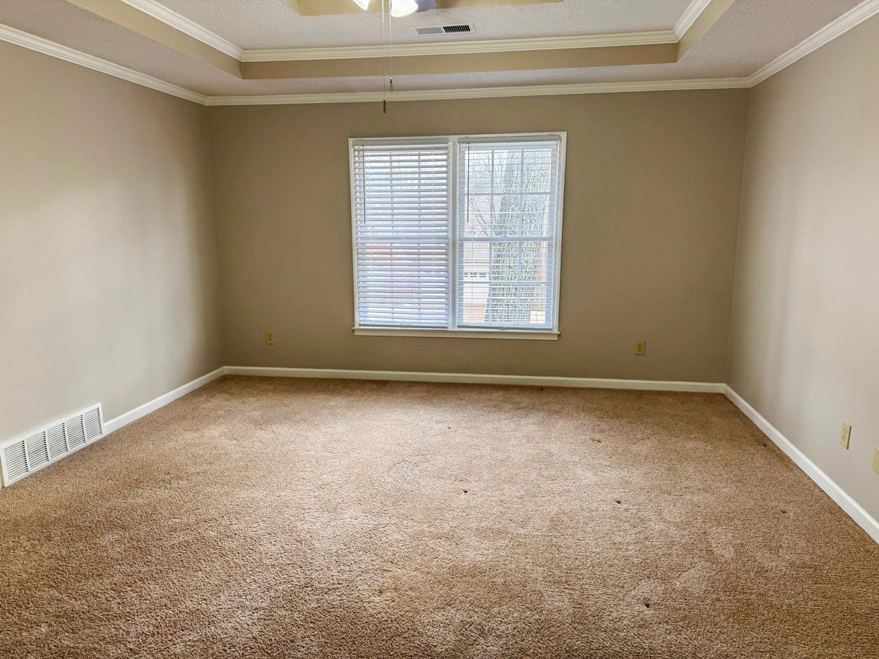 8810 Raspberry Lane Memphis, TN 38016 - Photo 18 of 28 Empty room with visible vents, crown molding, and a raised ceiling