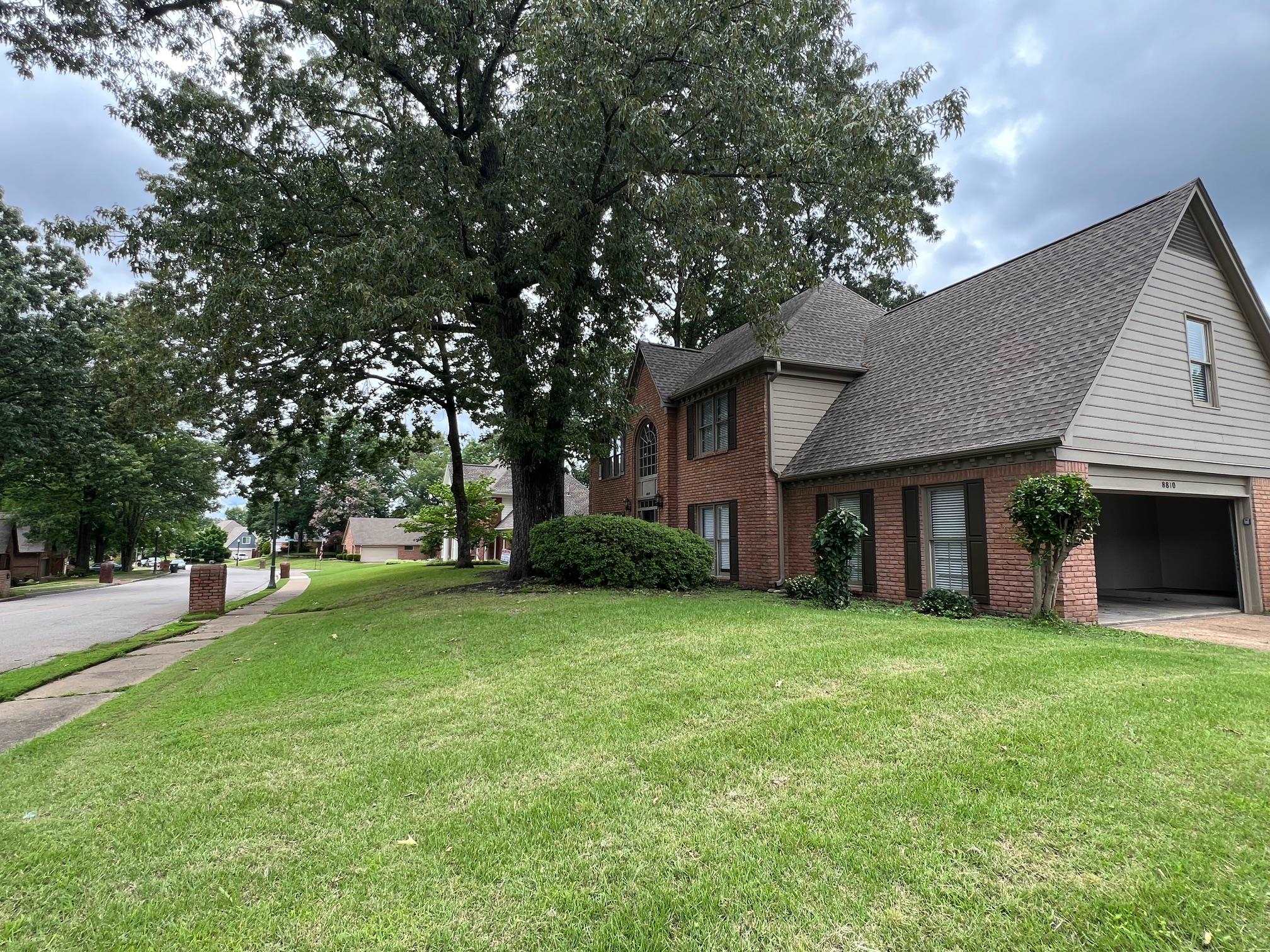 8810 Raspberry Lane Memphis, TN 38016 - Photo 2 of 28 View of front of home featuring brick siding, a shingled roof, a front yard, and a garage