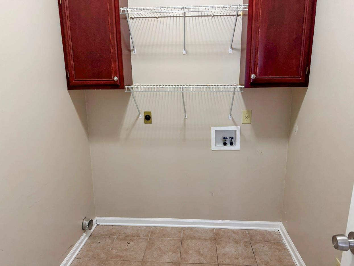 8810 Raspberry Lane Memphis, TN 38016 - Photo 5 of 28 Laundry area with washer hookup, baseboards, hookup for an electric dryer, cabinet space, and light tile patterned floors