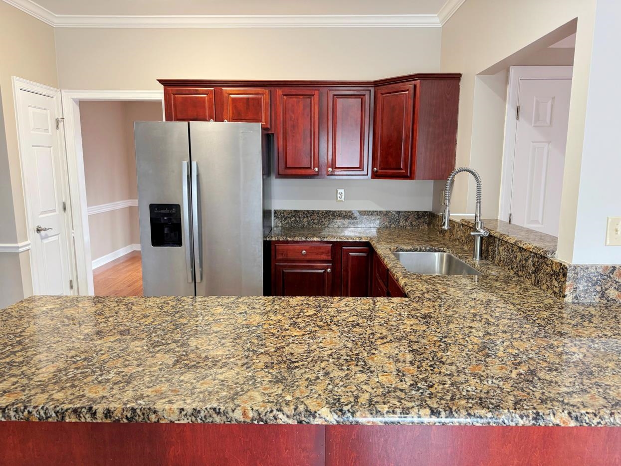 8810 Raspberry Lane Memphis, TN 38016 - Photo 7 of 28 Kitchen featuring crown molding, stainless steel fridge with ice dispenser, reddish brown cabinets, and a sink